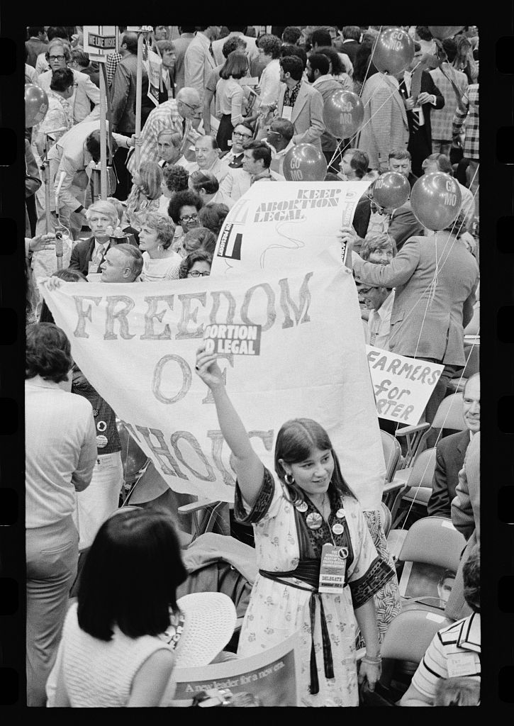 A black and white photograph of a crowd of male and female demonstrators protesting with pro-choice signs that read 