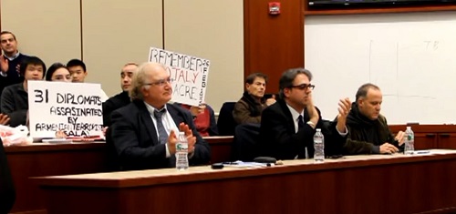 Holding signs with provocative slogans, protesters flank a panel of prominent Armenologists. From left: Simon Payaslian, Marc A. Mamigonian, and James R. Russell. Still from "Armenia 1915-Auschwitz 1945: Small Nations and Great Powers," https://youtube/watch?v=jqPpXPAfNEk.
