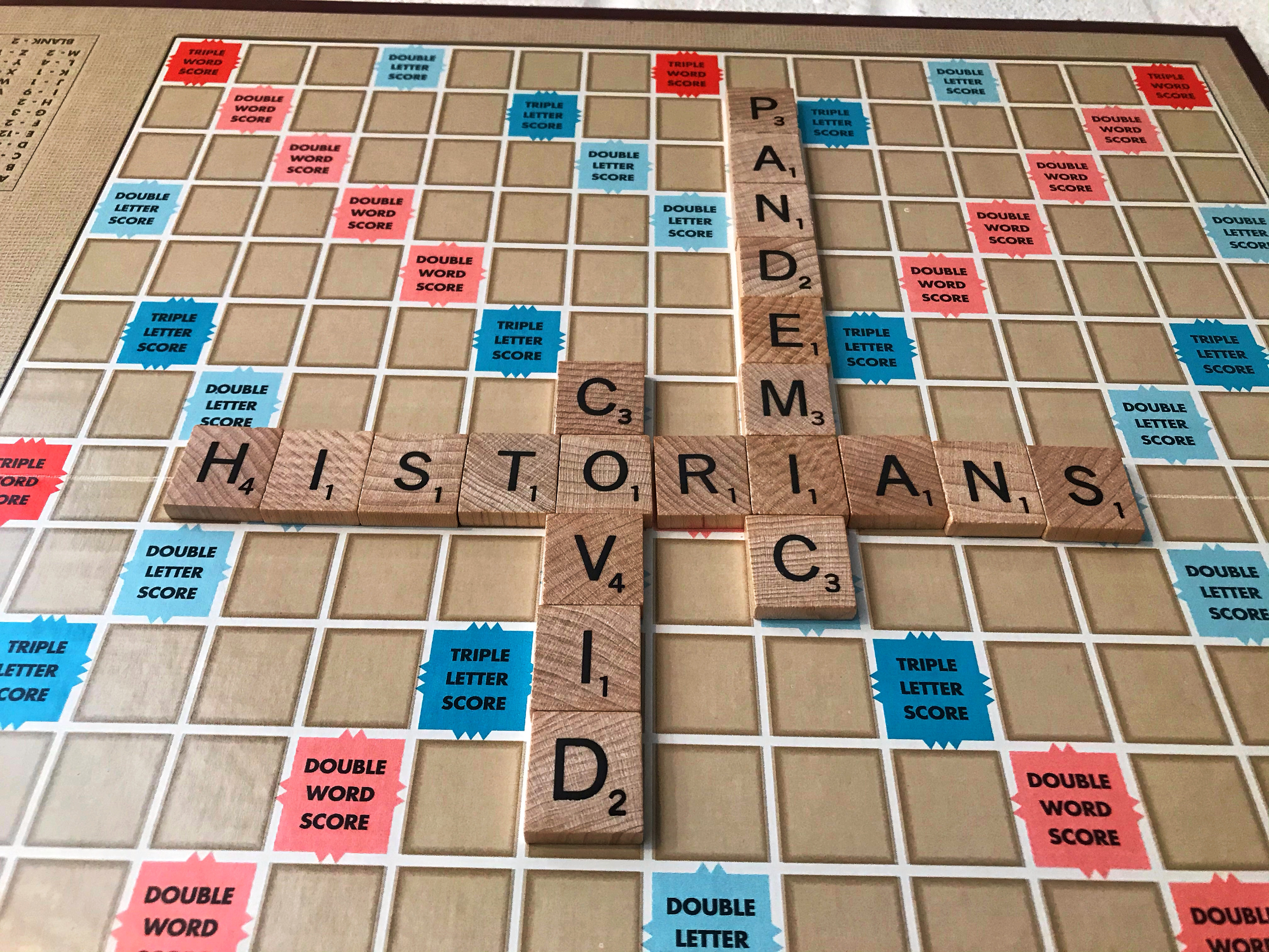 Photo of a Scrabble board, spelling out “historians” horizontally and “COVID” and “pandemic” vertically.