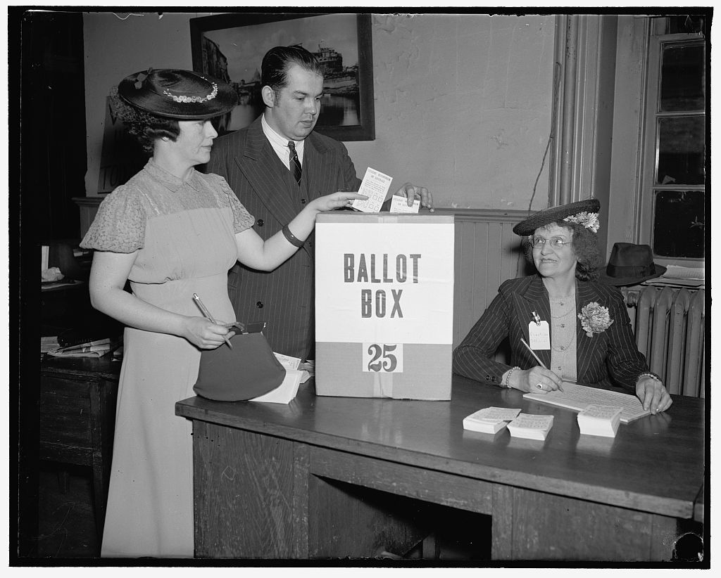 Black and white photo of two individuals casting their ballots.