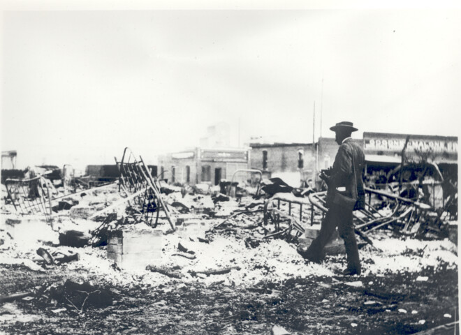 An African American photographer surveying the damage after white Tulsans destroyed the physical manifestations of their Black neighbors' successes.