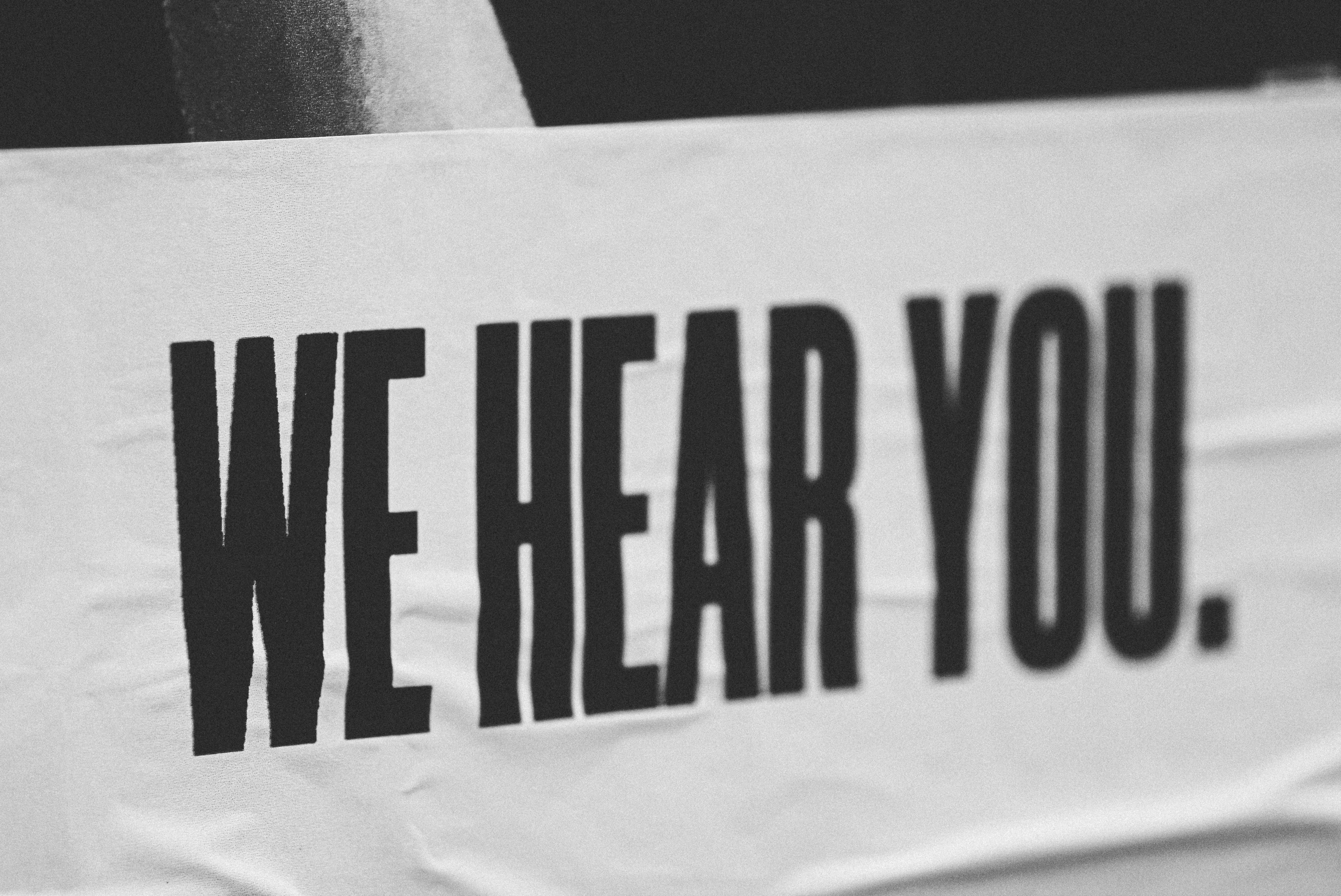 A white banner with “We Hear You.” in black block letters.