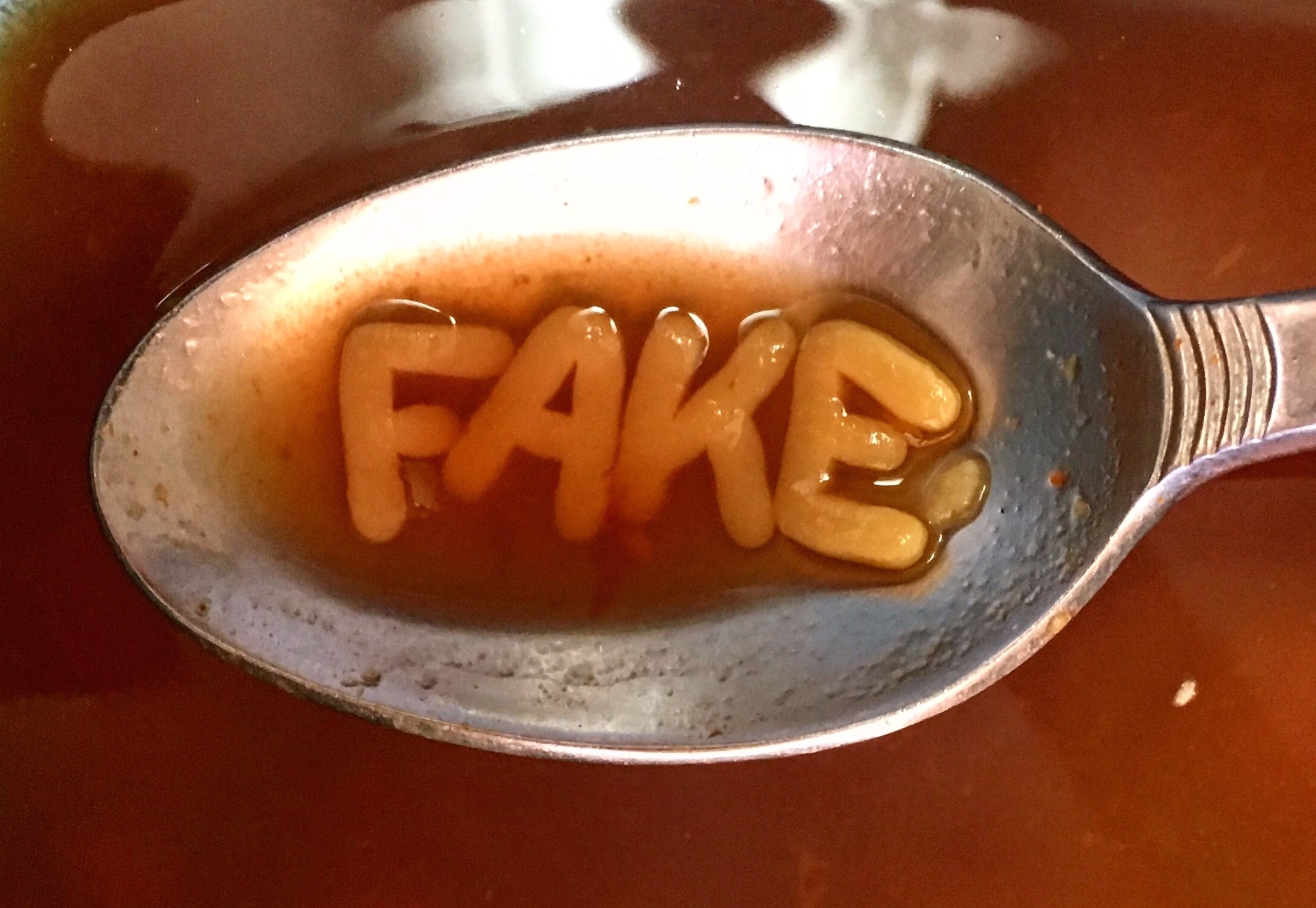 A spoonful of tomato alphabet soup, containing the letters F A K E.
