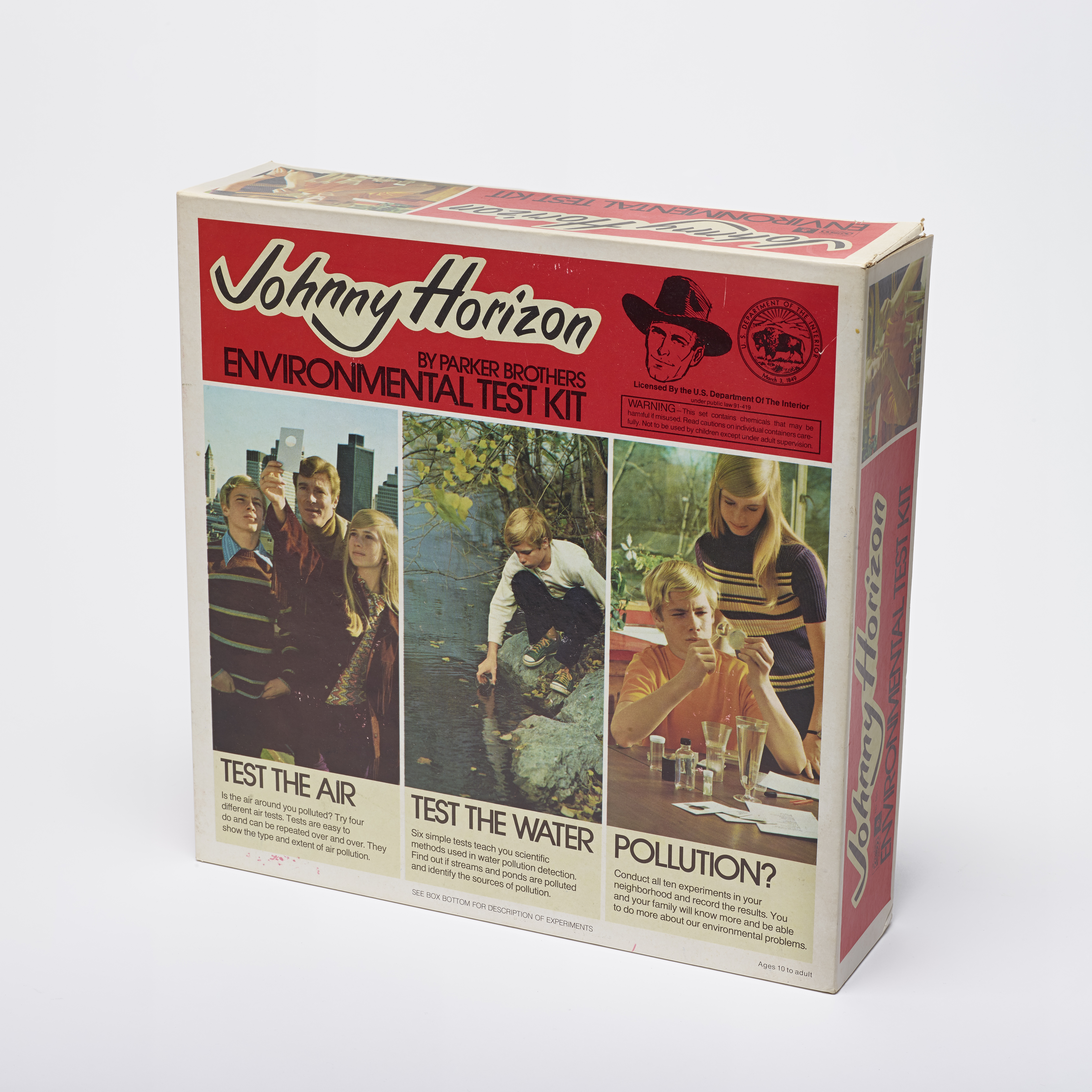 A faded box cover for a Johnny Horizon Environmental Test Kit. A red title bar gives the product’s name next to the face of a man in a cowboy hat. Three vertical images show children engaged in using the kit with the titles “Test the Air,” “Test the Water,” and “Pollution?”