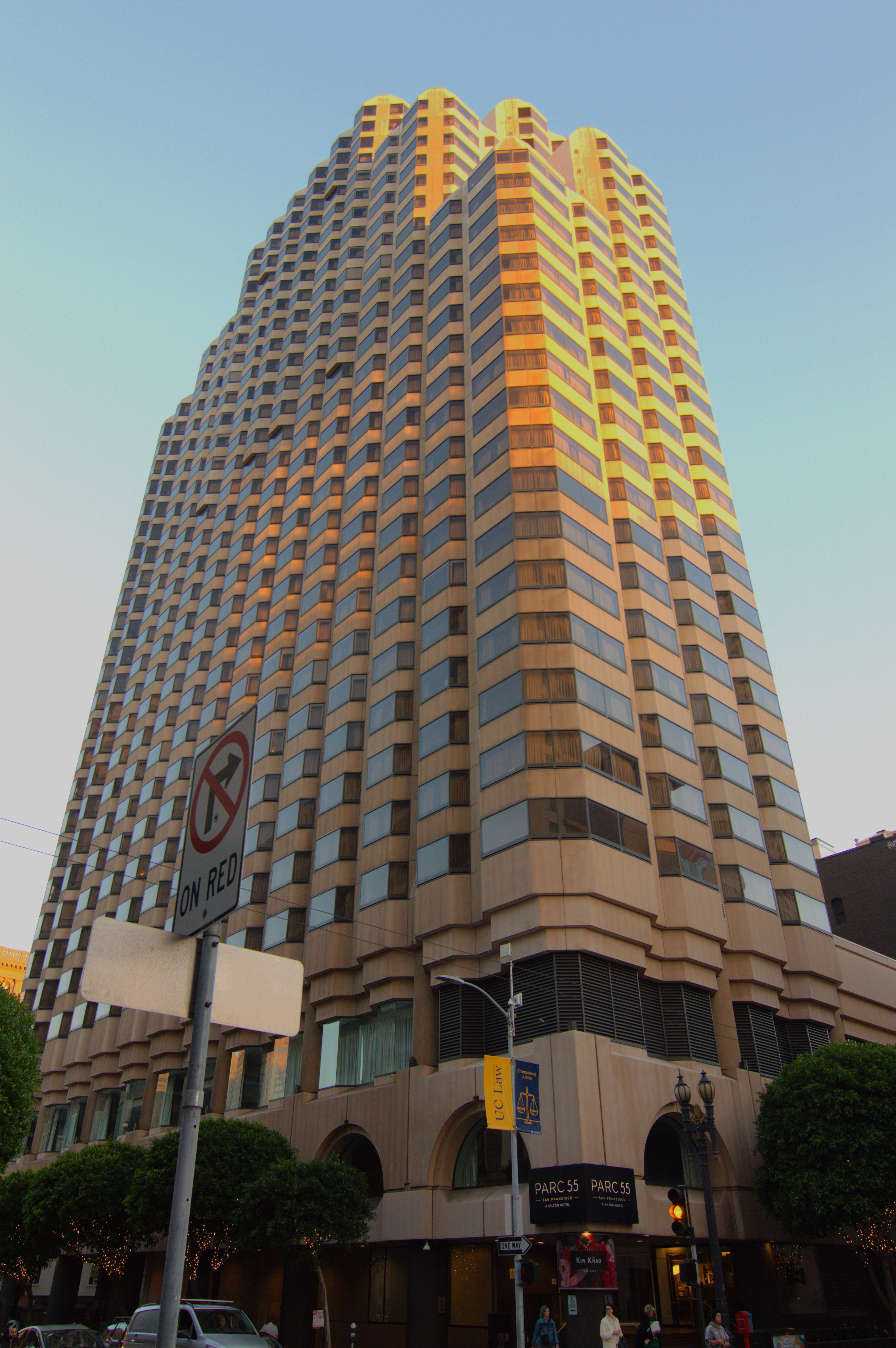 A large hotel building with the sun shining on its upper floors