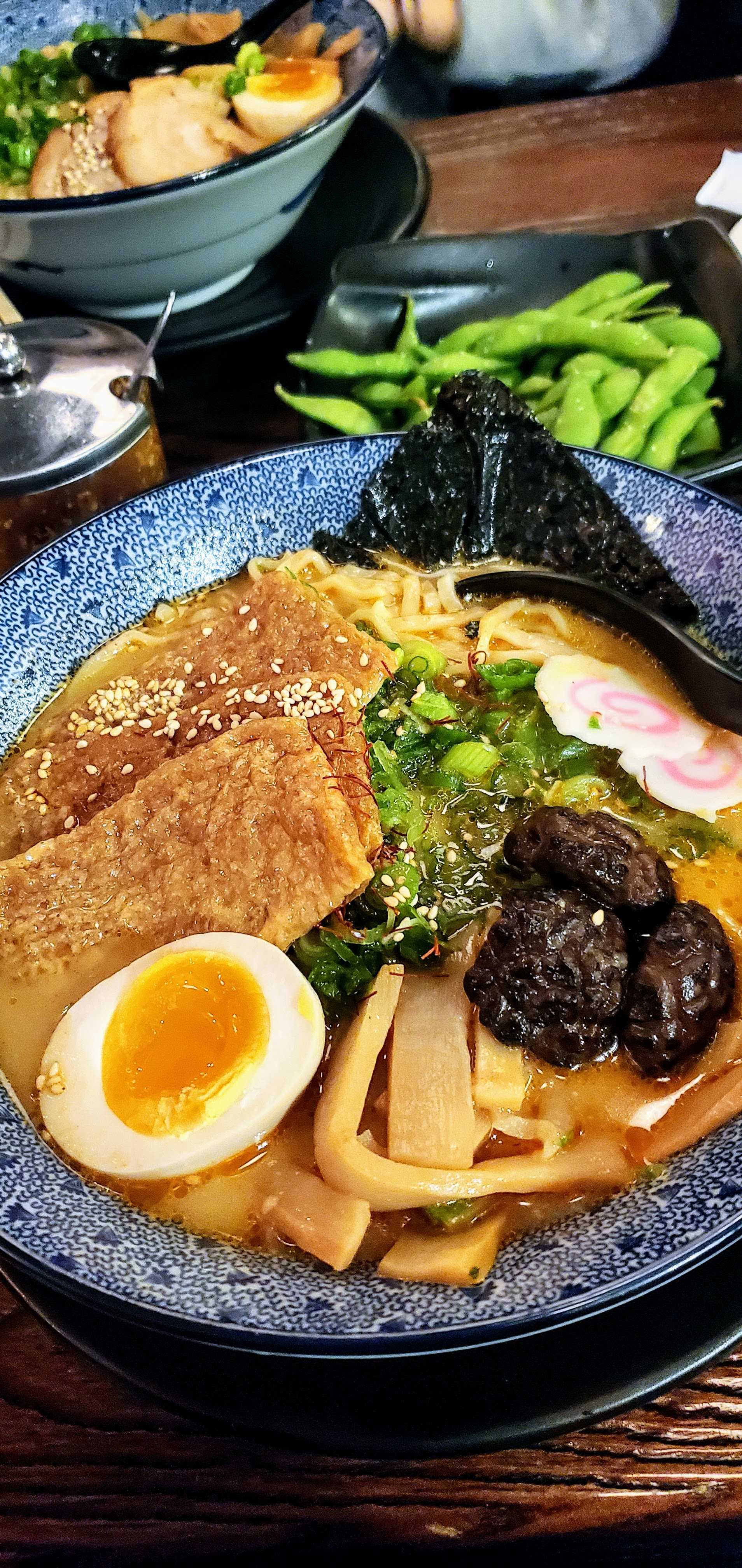 A bowl of ramen with tofu, seaweed, and an egg on top
