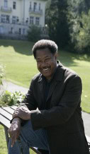Photograph of Thomas C. Holt posed on a bench in front of a green lawn and white building