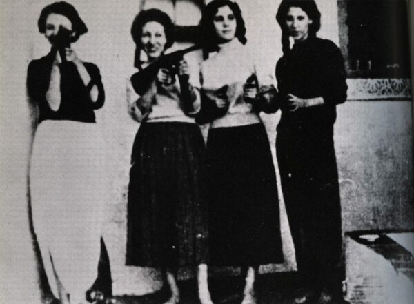Black and white photo of four women, on the left the women is taking a photo