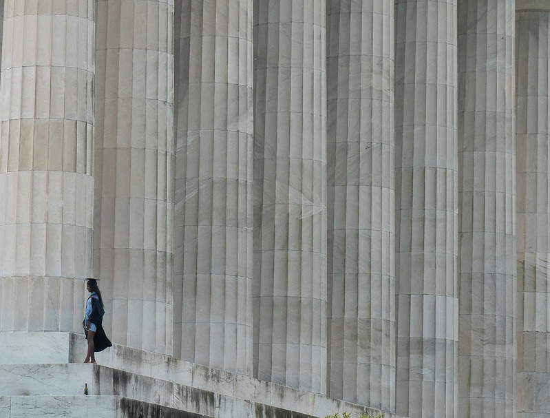 Six white columns in a row with a graduate walking up the steps.