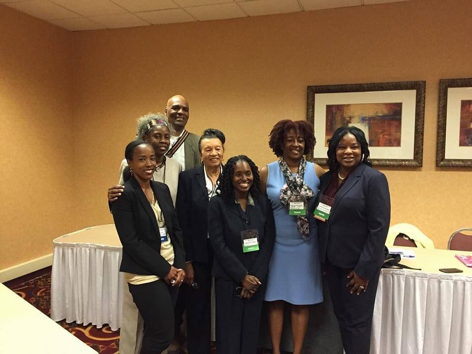 Color photograph of a group of adults inside a hotel conference room.