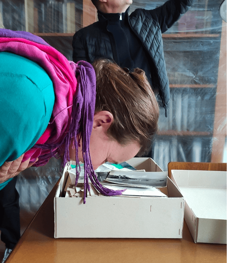 AHR_2023_KnowingbySensing A person leaning over a box sniffing its contents.