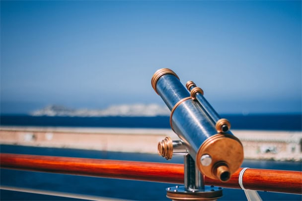 A blue telescope looking over a beach