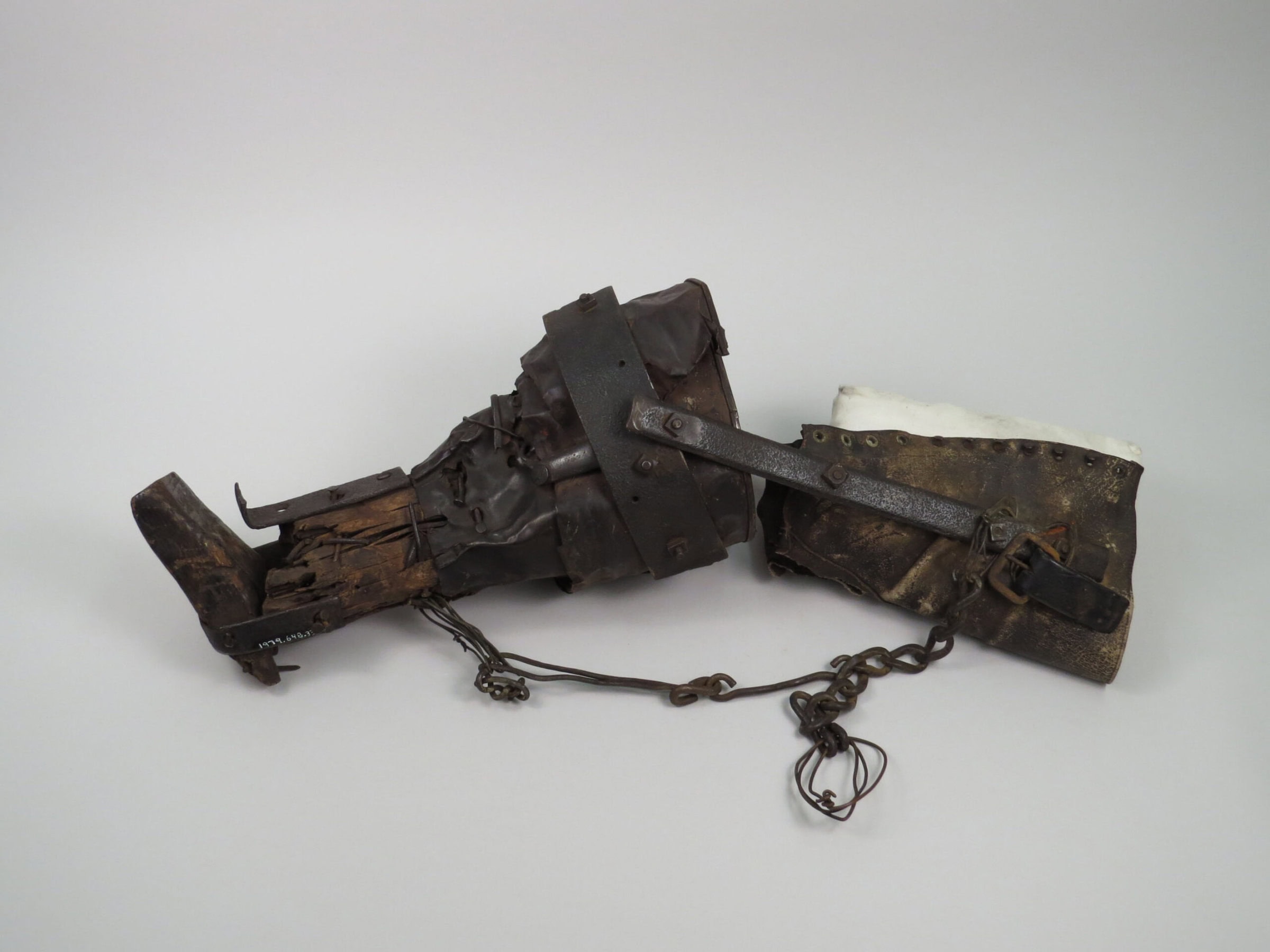 A prosthetic leg made from a metal bucket for the socket, nails, chain and chicken wire for securing the parts, and a leather boot.