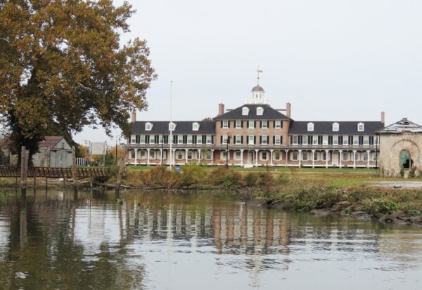A large pink building with a green roof overlooking a lake.
