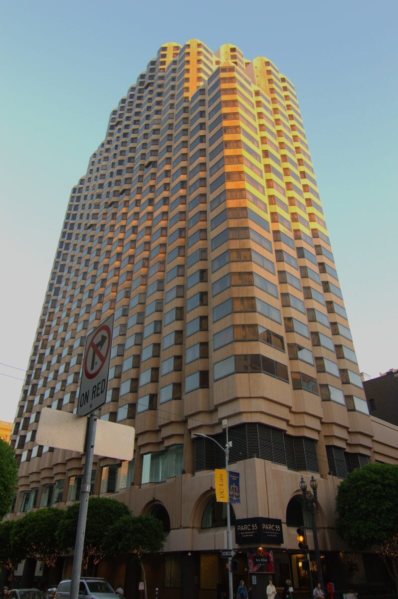 A large hotel building with the sun shining on its upper floors