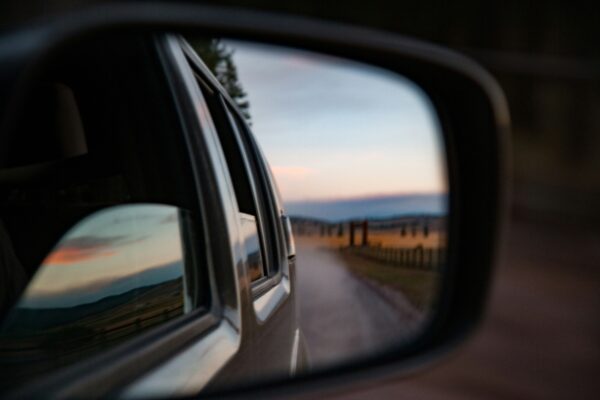 A rearview mirror reflecting a road in the desert