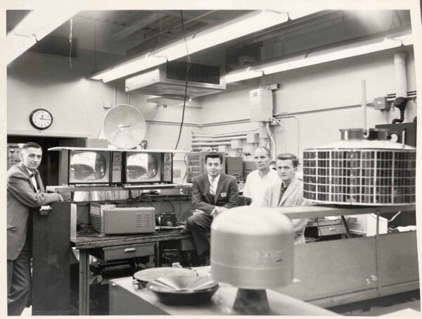 Four scientists in a lab with a satellite