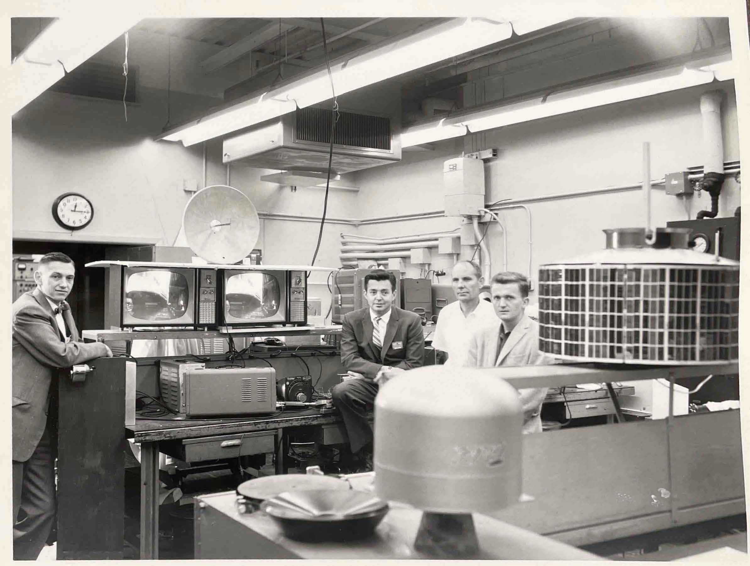 Four scientists in a lab with a satellite
