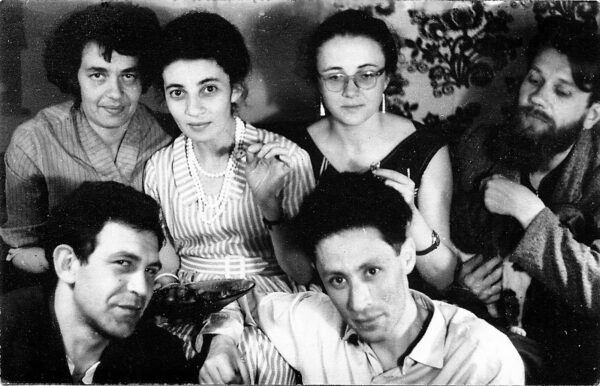Black and white casual photograph of three women and three men sitting together