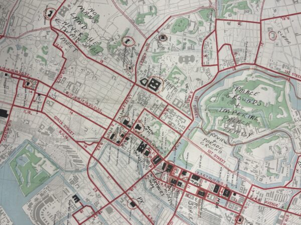 A vintage map depicting the city of Tokyo, highlighting major landmarks and areas with red outlines. Handwritten notations appear throughout the map