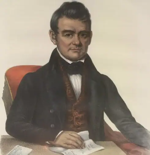 Image of a man in formal wear sitting at a desk or table with a document in front of him.