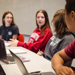 3 students sitting at a table with papers in front of them