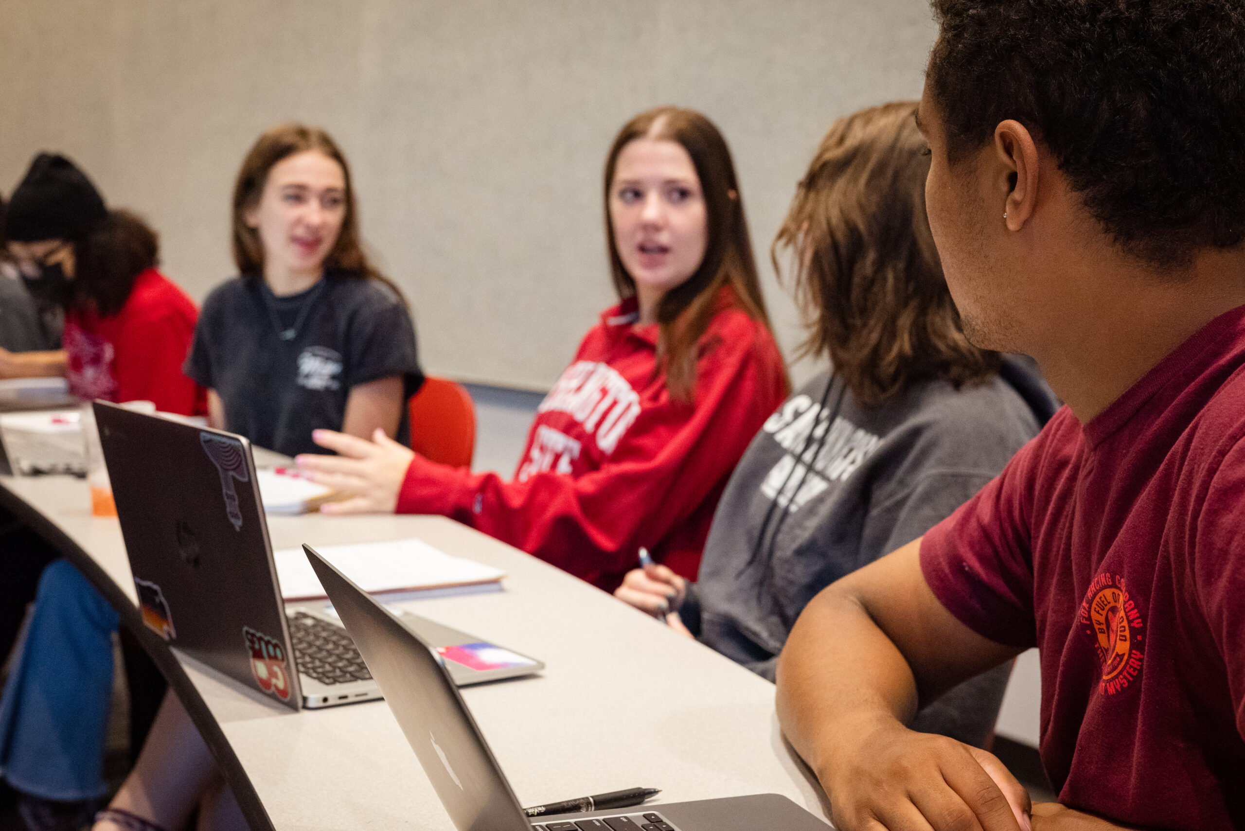 3 students sitting at a table with papers in front of them